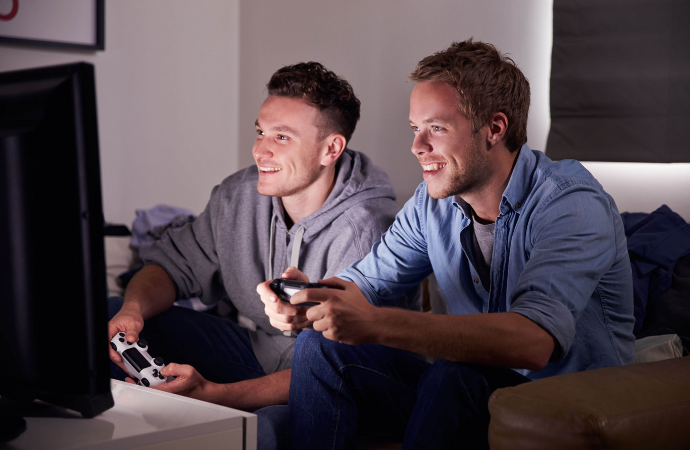 Two Young Men Playing Video Game At Home